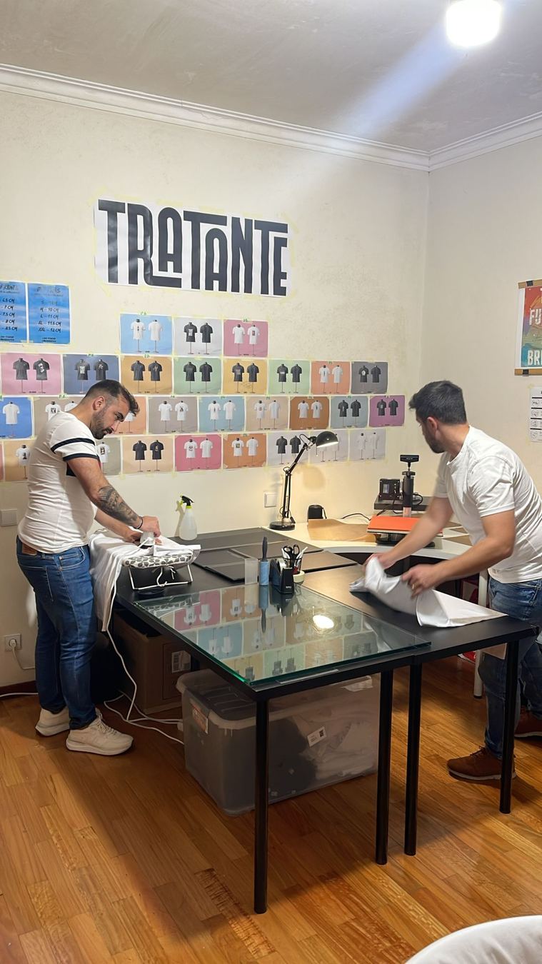 Dois fundadores a trabalhar numa mesa, com a parede de provas TRATANTE atrás