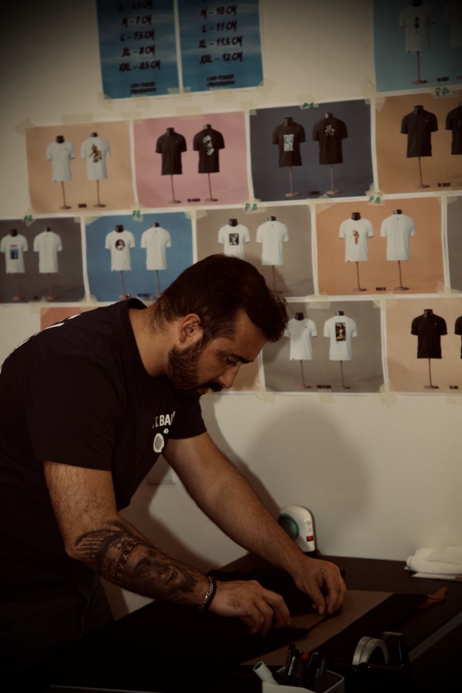 Parede com dezenas de provas de t-shirts em papel colorido