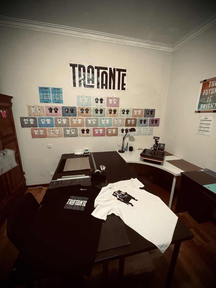 O quarto com a mesa de trabalho, a prensa e o logo TRATANTE na parede